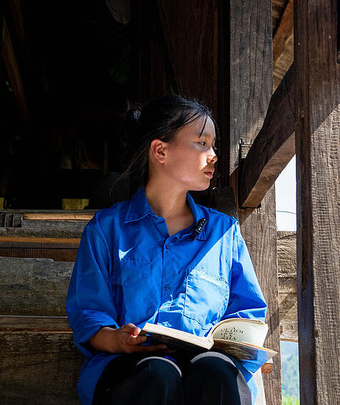 Ein vietnamesisches Mädchen sitzt auf einer Treppe und hat in Buch in der Hand