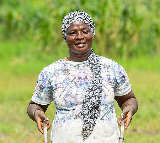 Reisbäuerin Paulina (44) aus Ghana stand zeitlebens vor immensen Herausforderungen Eine Frau hält eine Landmaschine in den Händen und lacht