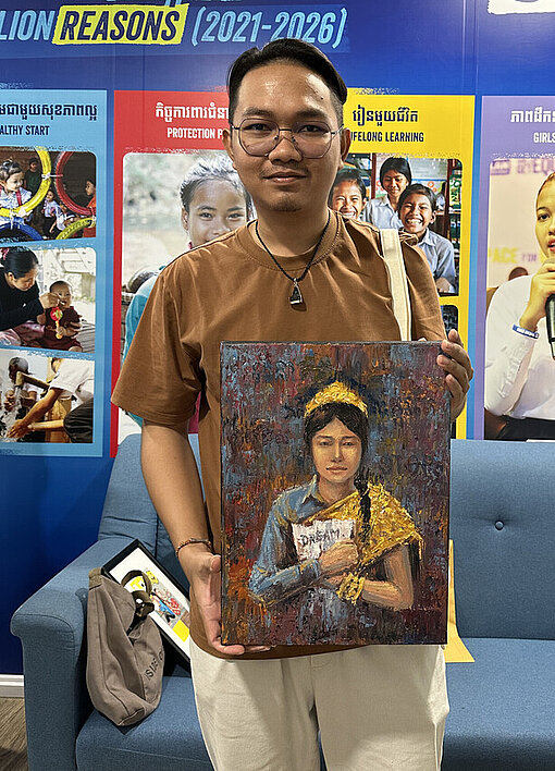Ein kambodschanischer junger Mann hält ein Kunstwerk in der Hand