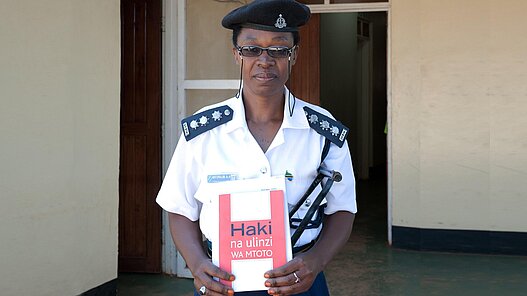 Polizistin in der Provinz Geita mit einer Broschüre "Rechte und Schutz von Kindern".
