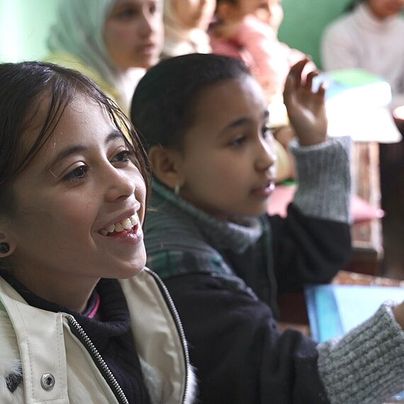 Ein Mädchen sitzt lachend neben ihrer Klassenkameradin