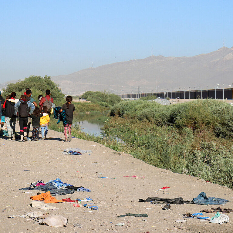 Gruppe geflüchteter Menschen in karger Landschaft auf dem Weg