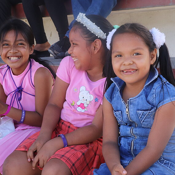 Drei Mädchen auf sitzen auf einer Tribüne und lachen