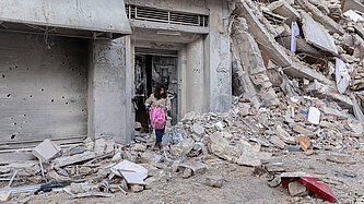 Eine Frau holt eine Tasche aus den Trümmern eines Gebäudes