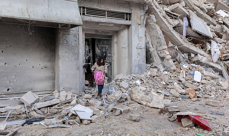 Eine Frau holt eine Tasche aus den Trümmern eines Gebäudes