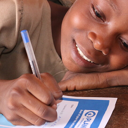 Ein Mädchen in Benin schreibt einen Brief an seine Pateneltern.
