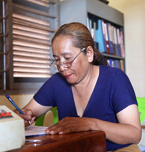 Sohen sitzt an einem Tisch und schreibt an einem Dokument in Kambodscha