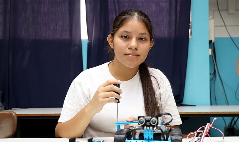 Mädchen schraubt an einem Roboter