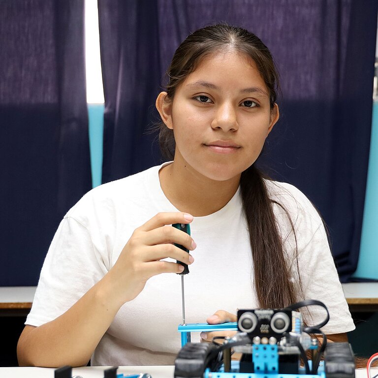 Mädchen schraubt an einem Roboter