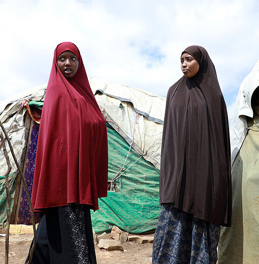 Hibo und Munira stehen im IDP-Camp vor ihrem Zelt 