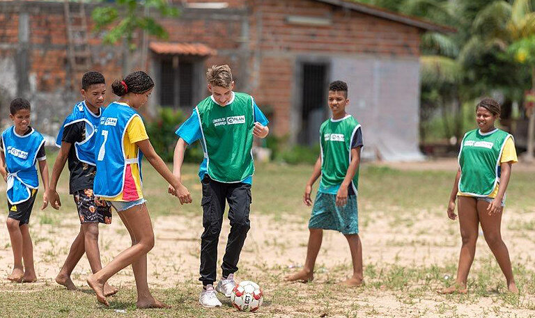 Kinder mit Leibchen spielen Fußball.