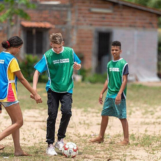 Kinder mit Leibchen spielen Fußball.