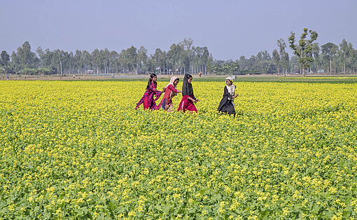 Mädchen in einem blühenden Feld in Bangladesch