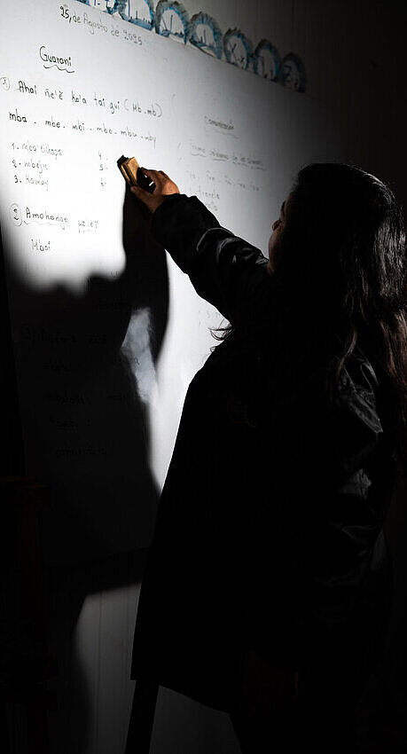 Eine Frau steht an einer Tafel und schreibt 