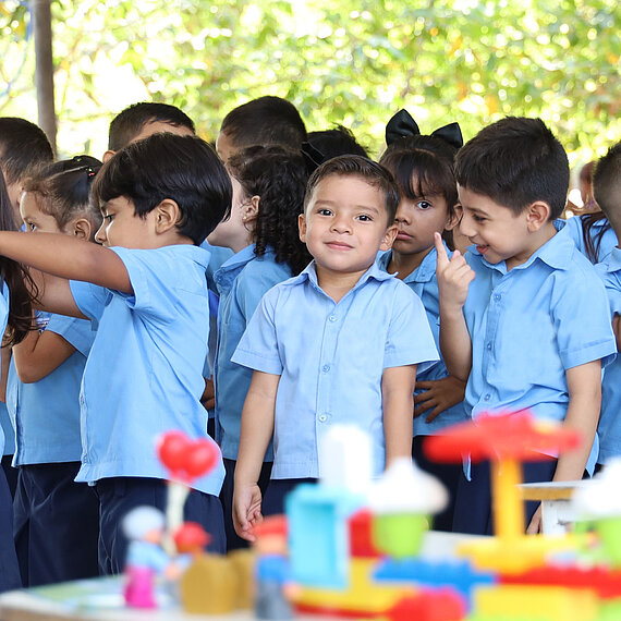 Ein Junge und weitere Kinder in hellblauen Hemden sprechen miteinander