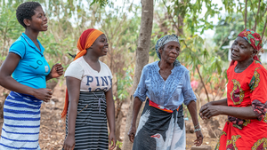 Frauen aus verschiedenen Generationen führen ein Gespräch unter Bäumen in Malawi