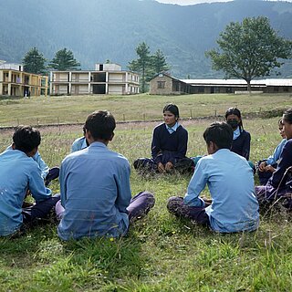 Kinder sitzen im Freien auf einer Wiese und halten ein Clubtreffen ab