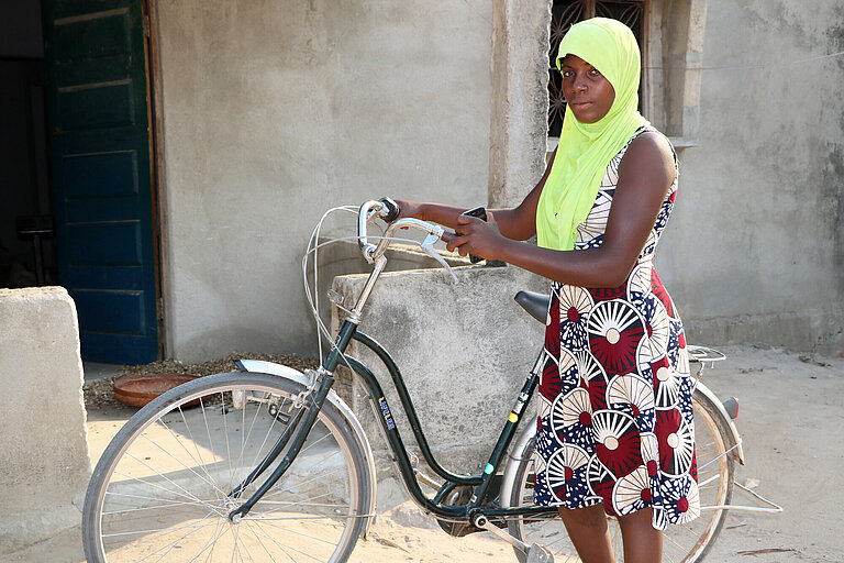 Ein Mädchen mit Kopftuch steht neben ihrem Fahrrad