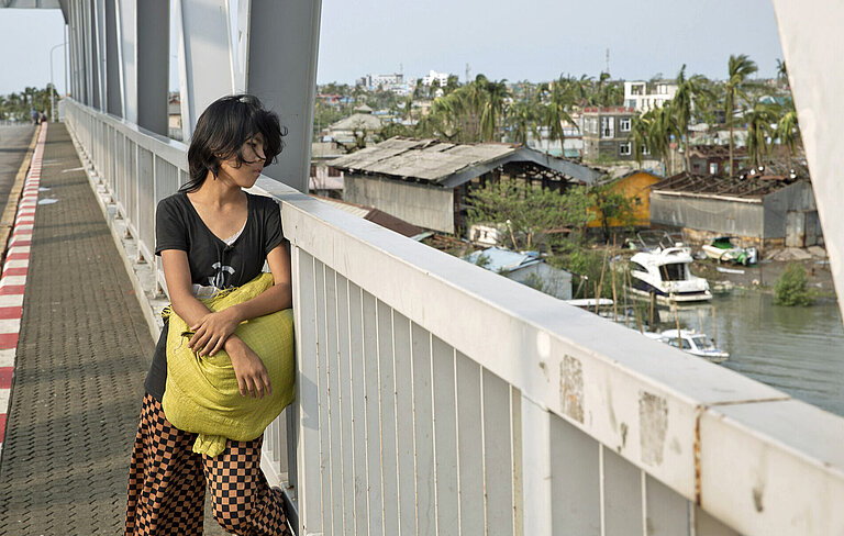 Eine junge Frau steht auf einer Brücke