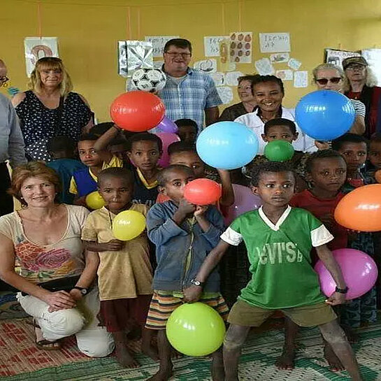 Pat:innen und Schulklasse halten Luftballons.