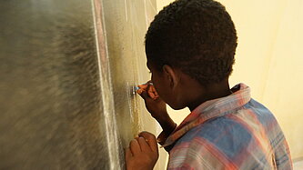 Junge schreibt an die Tafel