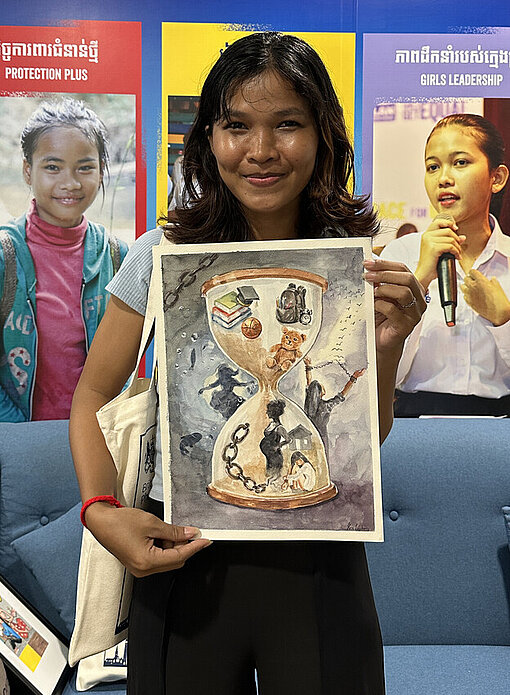 Eine kambodschanische junge Frau hält das Gemälde einer Sanduhr in der Hand