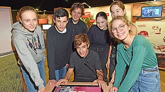 Mädchen und Jungen beugen sich über einen Tisch mit einer interaktiven Lernaufgabe