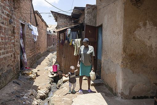 Faith und ihre Tochter stehen in der Gasse vor ihrem Zuhause