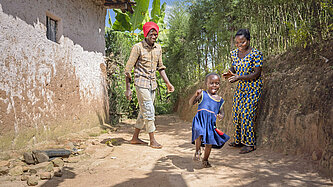 Ein kleines Mädchen spielt lachend und ihre Eltern schauen zu