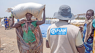 In Südsudan verteilen Plan-Teams Nahrungsmittel an bedürftige Frauen und Familien