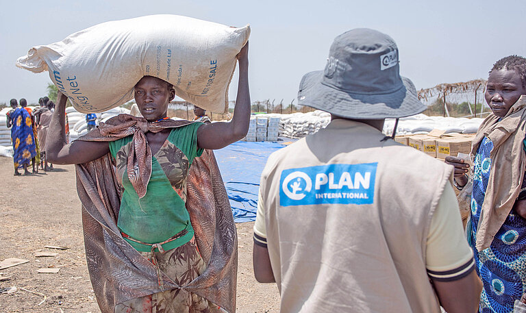 In Südsudan verteilen Plan-Teams Nahrungsmittel an bedürftige Frauen und Familien