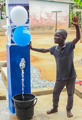 Ein Junge freut sich über den neuen Brunnen.