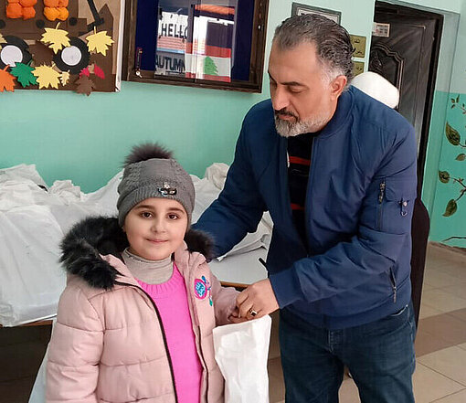 Ein Mädchen erhält ihre neue Schulausstattung von einem Plan Mitarbeiter 