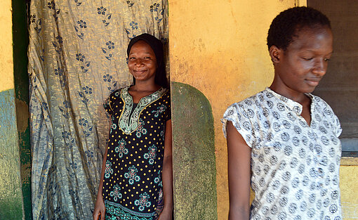 Fatouma und Koumba stehen mit Abstand vor einer Hauswand.