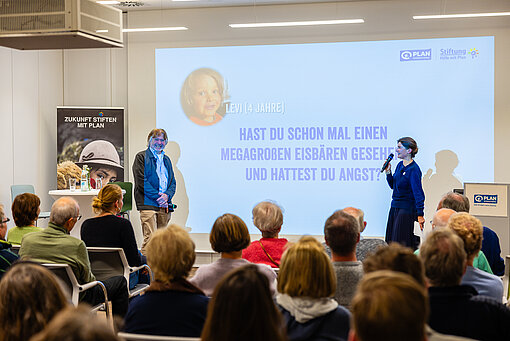 Arved Fuchs und Moderatorin auf Stiftungsevent, Kinderfrage zum Eisbären auf Leinwand.