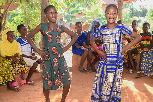 Anne tanzt mit einer Freundin, um sie herum sitzen Menschen im Kreis