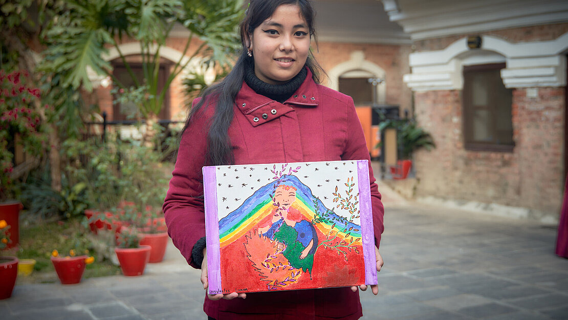 Eine junge Frau hält eine bemalte Leinwand in den Händen
