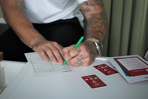 Man sieht ein Papier auf dem Tisch und die Hände von Jan Möller. Er hält einen Stift in der linken Hand und unterschriebt das Papier.
