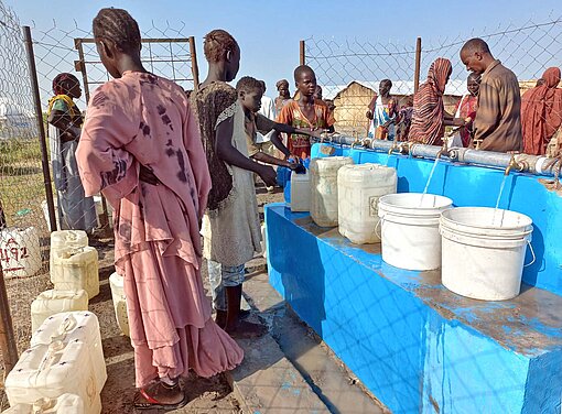 Menschen warten auf Wasserausgabe