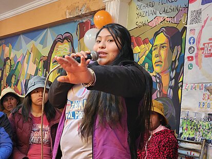 Eine junge Frau spricht auf einer Veranstaltung in ein Mikrofon