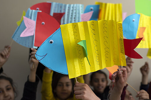 Kinder halten bunte aus Papier gebastelte Fische in die Höhe