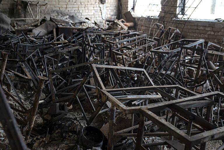 In einem Raum stapeln sich hunderte Metallgestelle von abgebrannten Tischen.