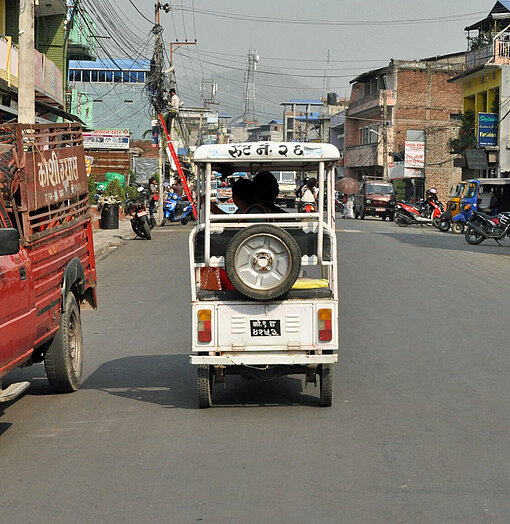 Ein nepalesisches Lasttaxi rollt nahe der Grenze zu Indien über dunklen Asphalt