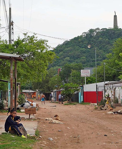 Blick auf einen sandigen Weg, an dem einfache Häuser aus Stein stehen