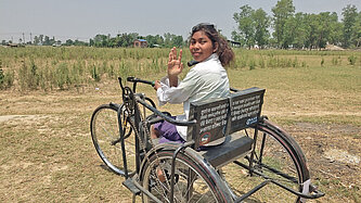 Ein Mädchen in Nepal sitzt in einem dreirädrigen Rollstuhl